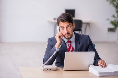 Genç erkek çalışan işyerinde oturuyor.