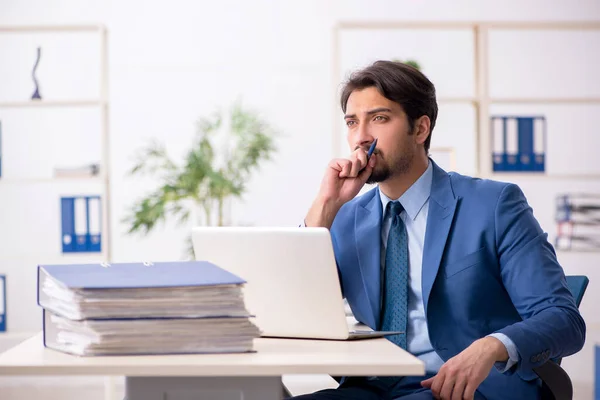 Ung manlig anställd och för mycket arbete på kontoret — Stockfoto