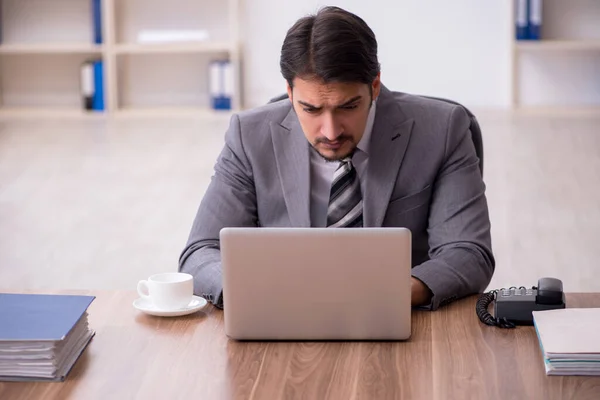 Jovem atraente masculino empregado sentado no local de trabalho — Fotografia de Stock