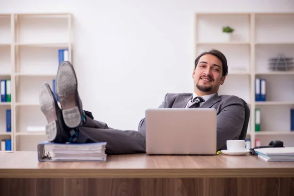 Joven empleado masculino atractivo sentado en el lugar de trabajo — Foto de Stock