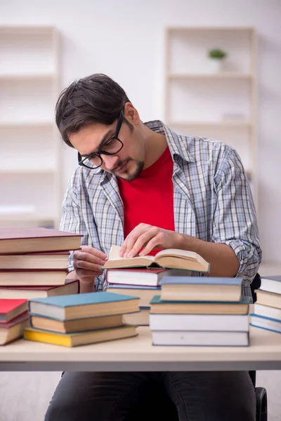 Jovem estudante do sexo masculino e muitos livros em sala de aula — Fotografia de Stock