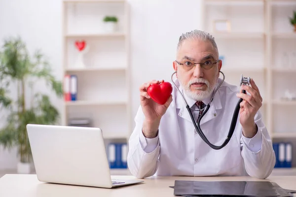 Viejo médico cardiólogo que trabaja en la clínica — Foto de Stock