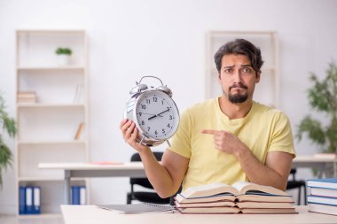 Genç erkek öğrenci zaman yönetimi konsepti sınavlarına hazırlanıyor.
