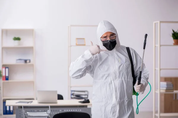 Contratista masculino joven desinfectando oficina durante pandemia — Foto de Stock