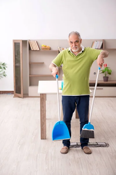 Oude man die het huis schoonmaakt — Stockfoto