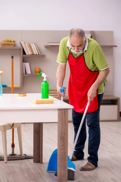 Oude man die het huis schoonmaakt — Stockfoto