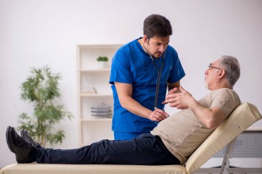 Yaşlı erkek hasta, genç doktor.