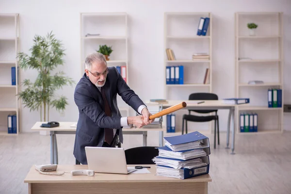 Старый работник мужчина недоволен чрезмерной работой в офисе — стоковое фото