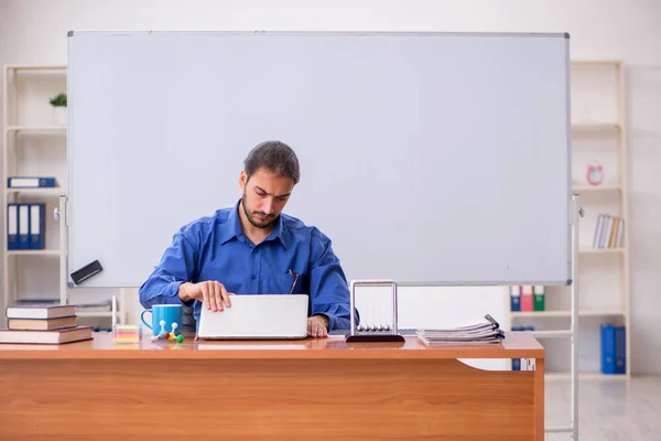 Młody mężczyzna nauczyciel fizyk siedzi w klasa — Zdjęcie stockowe