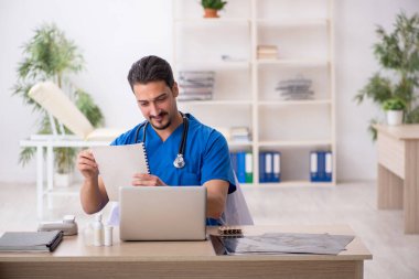 Klinikte çalışan genç erkek doktor.