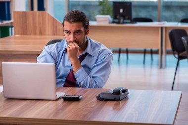 Ofisteki aşırı işten memnun olmayan genç bir erkek işçi.