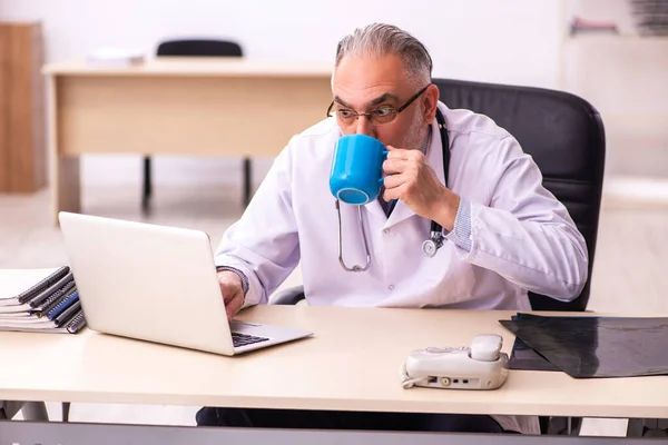 나이든 남성 의사가 클리닉에서 커피를 마시는 모습 — 스톡 사진