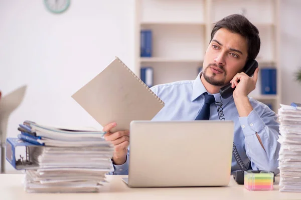 Ung manlig anställd och för mycket arbete på kontoret — Stockfoto