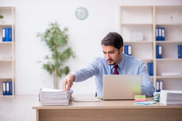 Ung manlig anställd och för mycket arbete på kontoret — Stockfoto