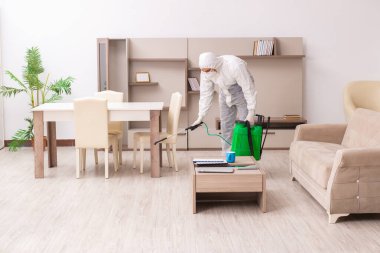 Genç erkek müteahhit evde haşere kontrolü yapıyor.