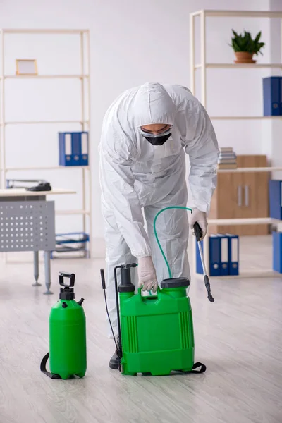 Contratista masculino joven desinfectando oficina durante pandemia — Foto de Stock