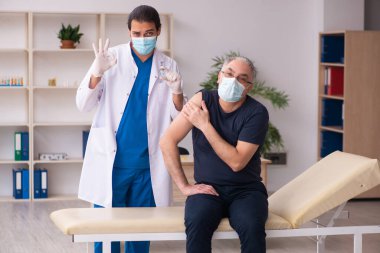 Yaşlı adam covid-19 aşı konseptinde genç doktoru ziyaret ediyor.