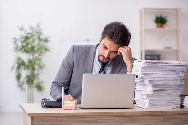 Joven empleado masculino y demasiado trabajo en la oficina — Foto de Stock