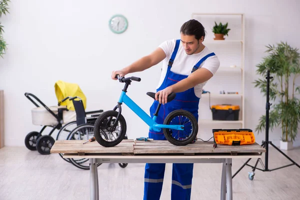 Junge männliche Reparaturkraft repariert Fahrrad im Haus — Stockfoto