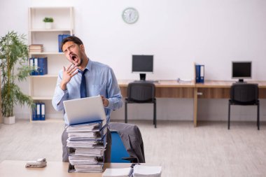 Genç bir erkek çalışan ve ofiste çok fazla iş var.