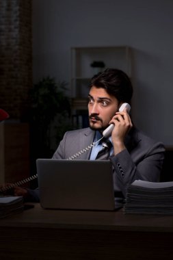 Genç erkek çalışan ofiste geç saatlere kadar çalışıyor.