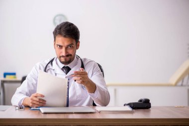 Klinikte çalışan genç erkek doktor.