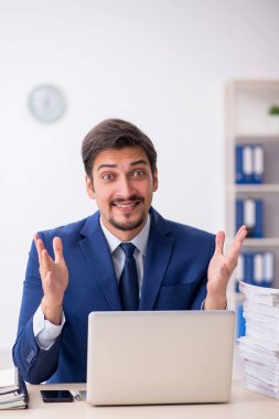 Genç bir erkek çalışan ve ofiste çok fazla iş var.