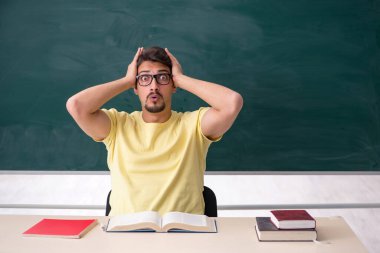 Tahtanın önünde genç bir erkek öğrenci.