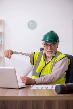 Ofiste çalışan yaşlı bir mimar.