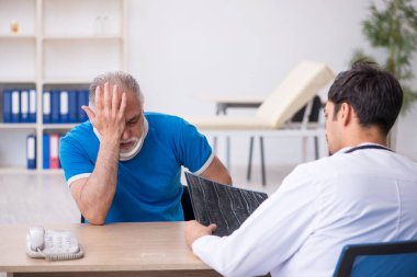 Yaşlı erkek hasta genç erkek doktor radyolojisti ziyaret ediyor.