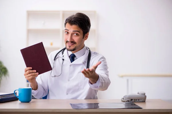 Jonge mannelijke arts die boek leest in de kliniek — Stockfoto