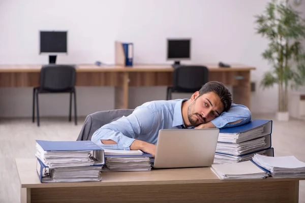 Jovem funcionário masculino e muito trabalho no escritório — Fotografia de Stock