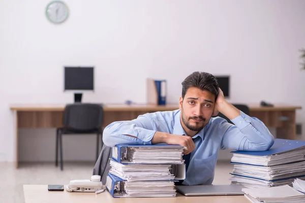 Joven empleado masculino y demasiado trabajo en la oficina — Foto de Stock