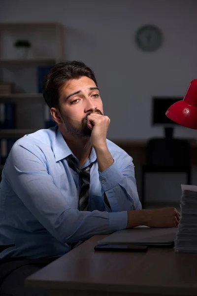 Jovem empregado do sexo masculino que trabalha até tarde no escritório — Fotografia de Stock