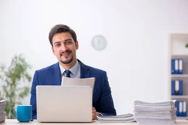 Jovem funcionário masculino e muito trabalho no escritório — Fotografia de Stock