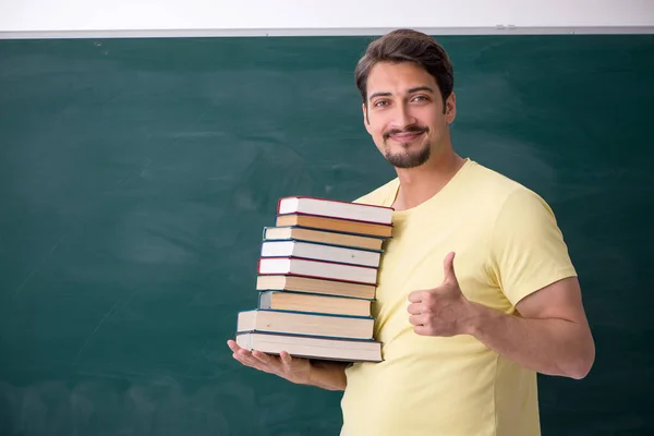 Jovem estudante do sexo masculino segurando muitos livros — Fotografia de Stock