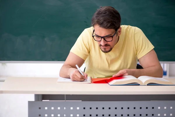 Joven estudiante masculino frente a pizarra — Foto de Stock