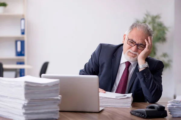 Velho empregado masculino e muito trabalho no escritório — Fotografia de Stock