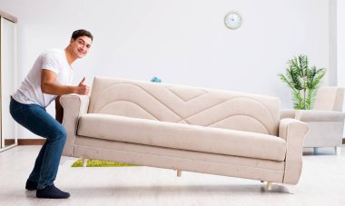 Genç adam evde mobilya taşıyor.