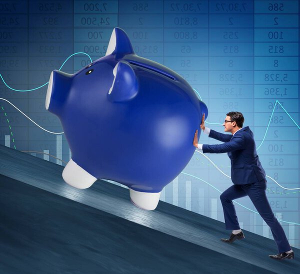 Man pushing piggybank uphill in business concept