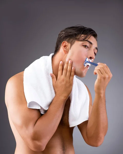 Handsome man shaving against dark background — Stock Photo, Image