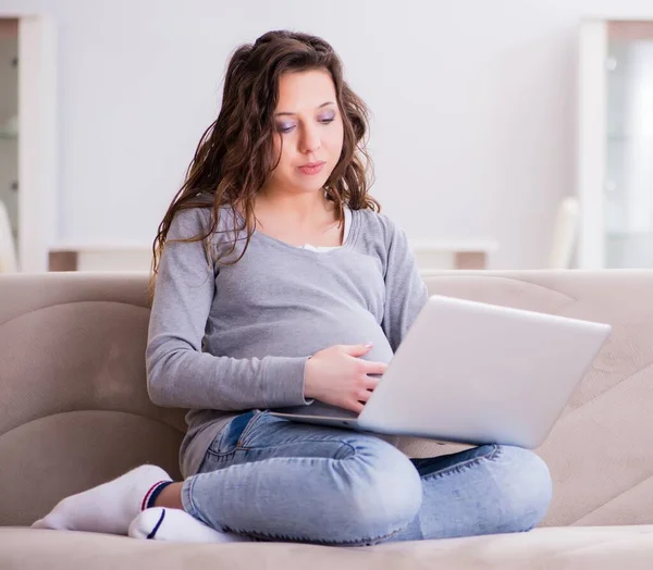 在笔记本电脑上工作的孕妇坐在沙发上 — 图库照片