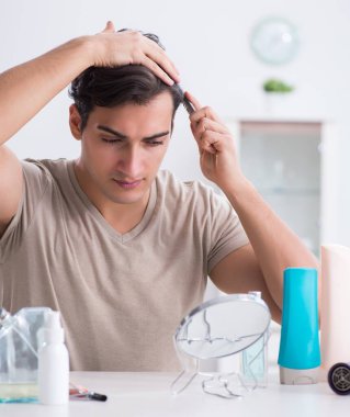 Genç yakışıklı adam aynaya bakıyor.