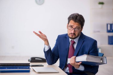 Ofisteki aşırı işten memnun olmayan genç bir erkek işçi.