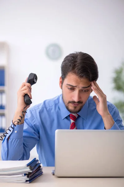 Jovem funcionário masculino infeliz com excesso de trabalho no escritório — Fotografia de Stock