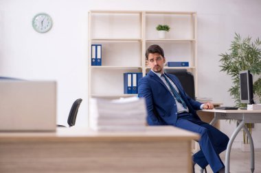 Genç bir erkek çalışan ve ofiste çok fazla iş var.