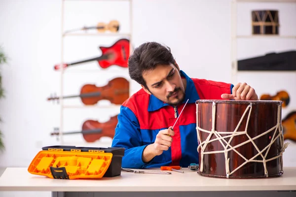 Mladý opravář mužského pohlaví opravuje na pracovišti hudební nástroje — Stock fotografie