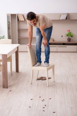 Genç adam ve evde bir sürü hamamböceği var.