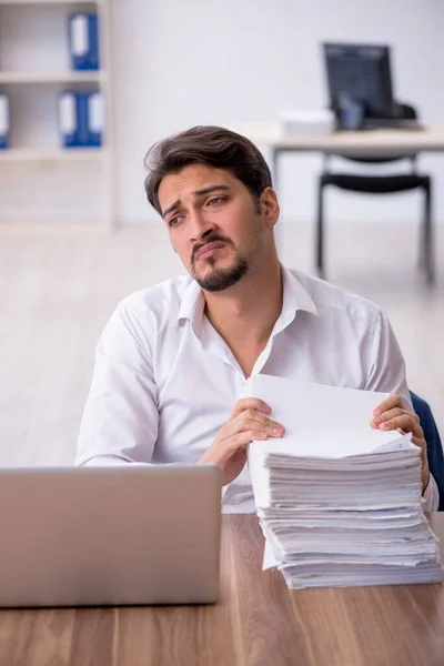 Joven empleado masculino y demasiado trabajo en la oficina — Foto de Stock