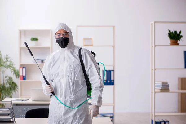 Contratista masculino joven desinfectando oficina durante pandemia — Foto de Stock